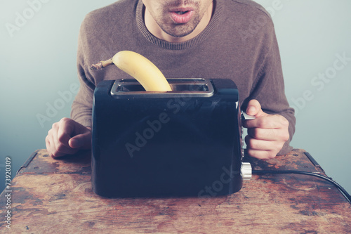 Young man trying to toast a banana photo