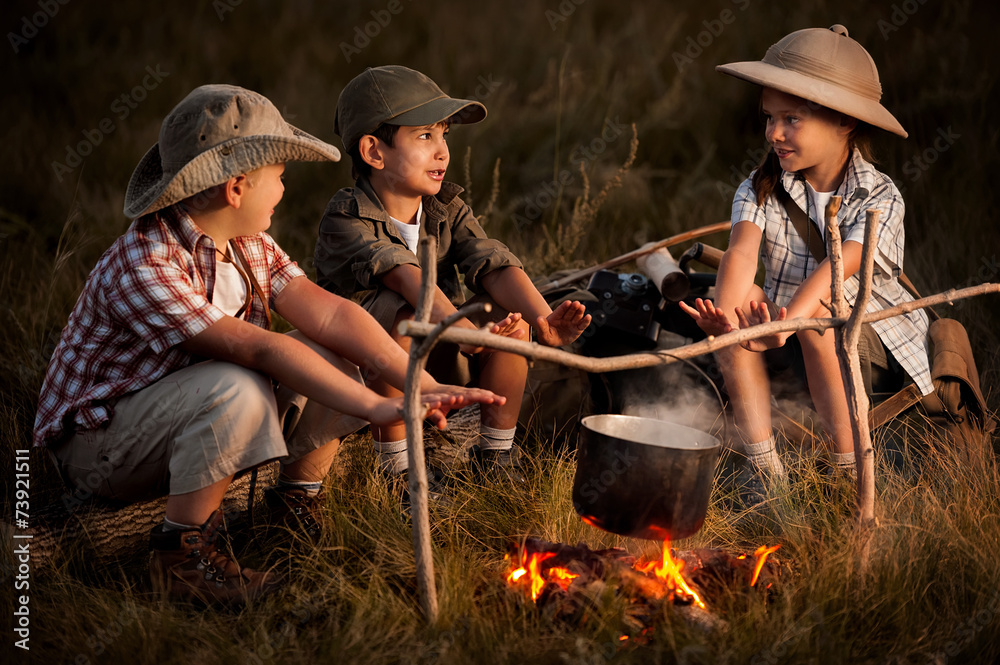 Fototapeta premium Group of children sitting around the campfire travelers