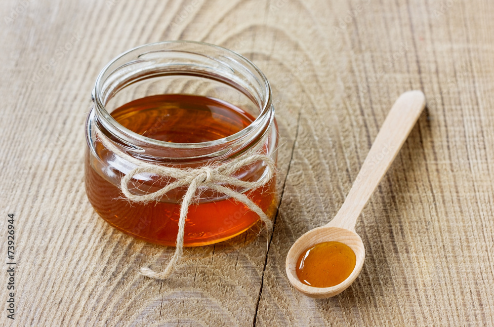Honey in a wooden spoon and jar Honey in a wooden spoon and jar
