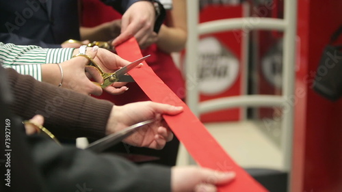 Opening. Ceremonial red ribbon cutting. Scissors in hands.