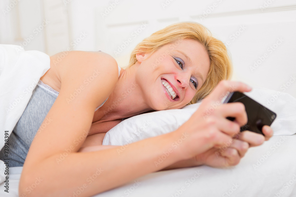 Young attractive woman sending ttext in a bed Young attractive woman sending ttext in a bed