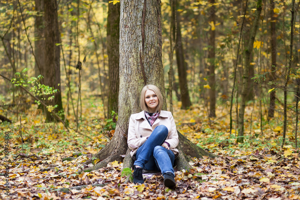 Blonde woman sitting under the tree in the forest Blonde woman sitting under the tree in the forest