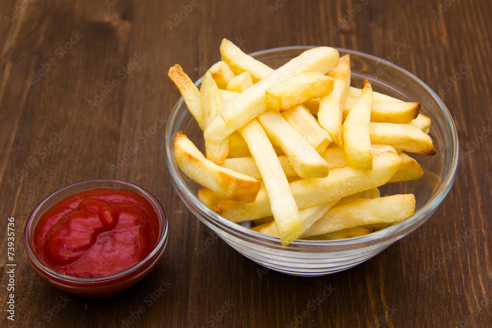 Bowl of chips and ketchup on wooden table Bowl of chips and ketchup on wooden table