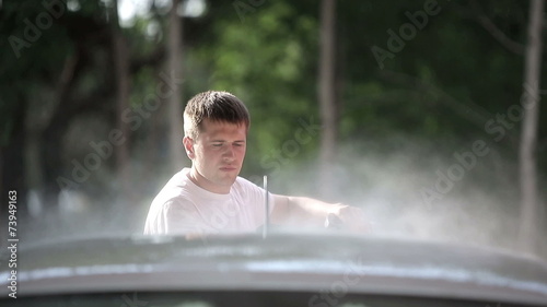 Man in a white t-shirt washes white car photo