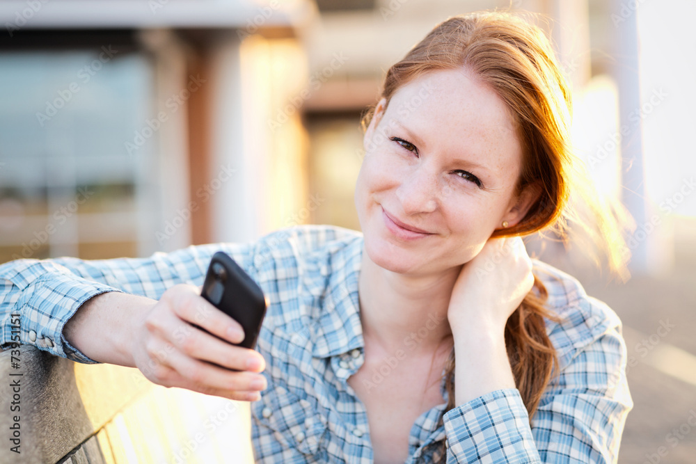 Young Woman Texting in a City at Sunset Young Woman Texting in a City at Sunset