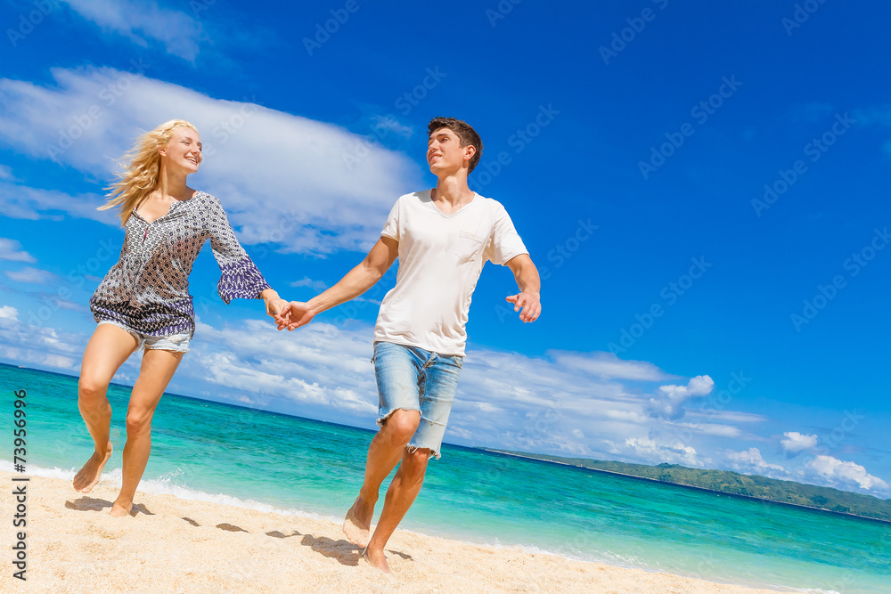 young happy couple running by sand beach on tropical sea backgro young happy couple running by sand beach on tropical sea backgro