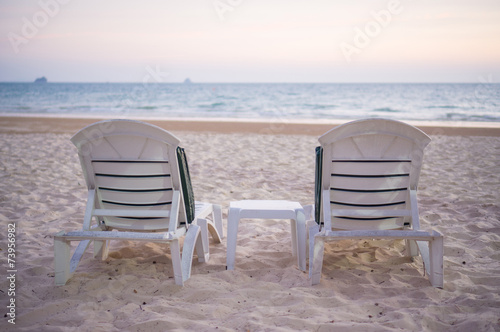 Two beach chairs on sunset in evening