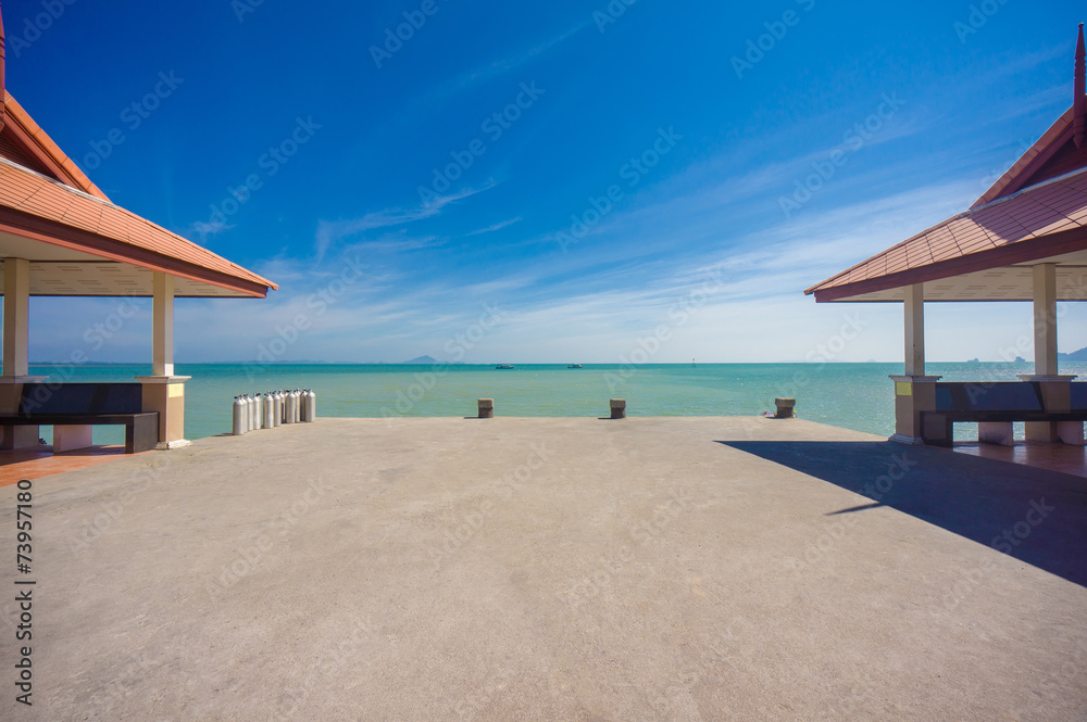 Long concrete pier on tropical beach with two canopy Long concrete pier on tropical beach with two canopy
