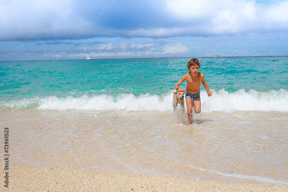 young happy child boy having fun with white dog in the sea, summ young happy child boy having fun with white dog in the sea, summ