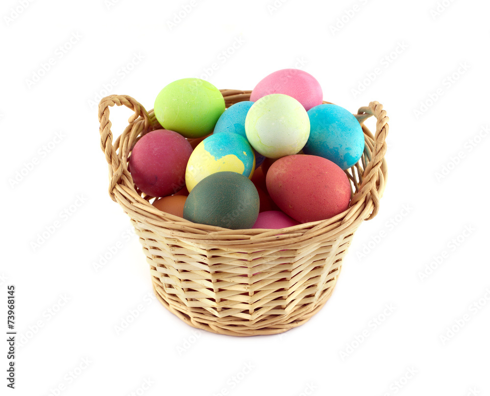 Colorful Easter eggs inside straw wicker brown basket isolated