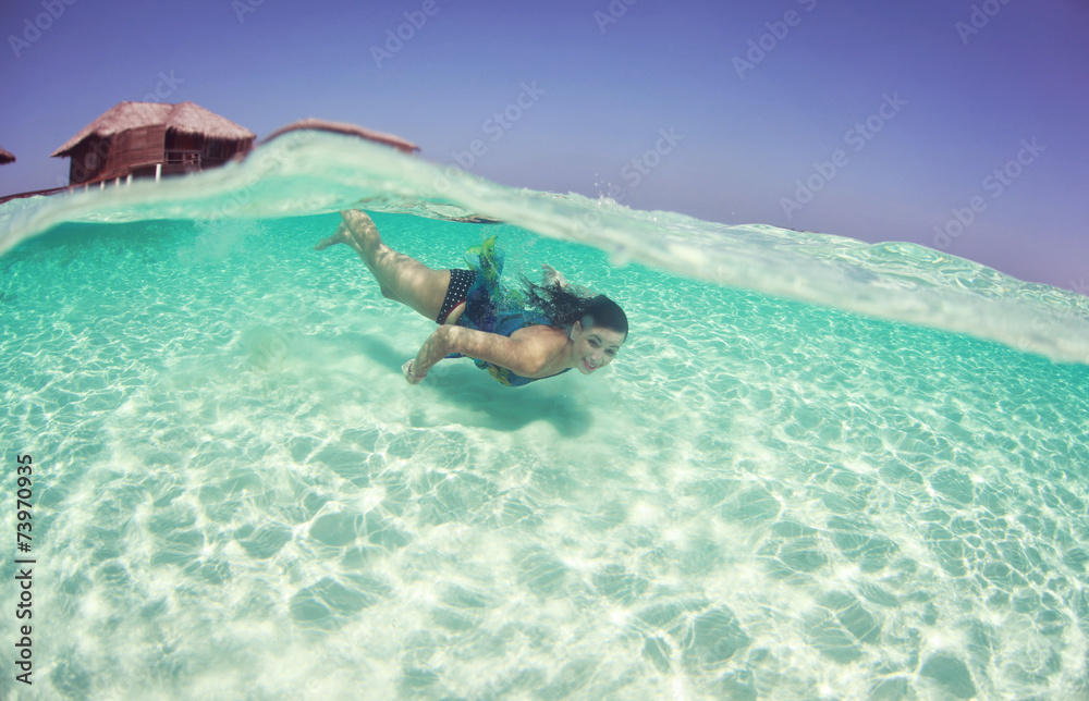 Happy woman in a dress swimmer in the ocean diving