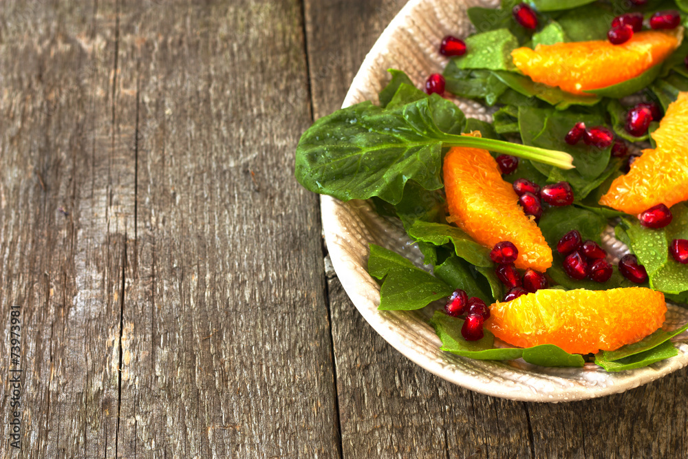 spinach salad, orange and pomegranate on a wooden background spinach salad, orange and pomegranate on a wooden background