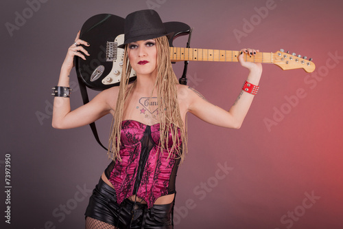beautiful punk girl with lots of tattoos posing with guitar