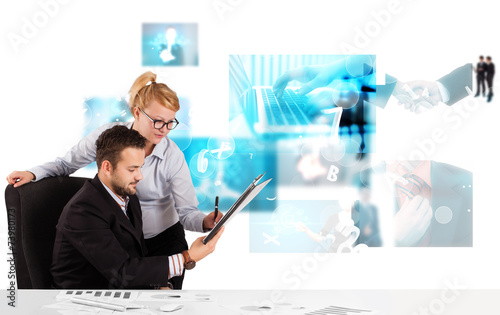 Business persons at desk with modern tech images at background