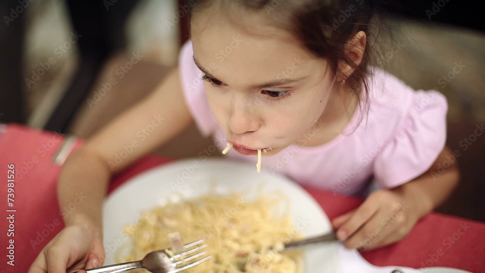Child eats spaghetti pasta in the restaurant near the sea Child eats spaghetti pasta in the restaurant near the sea
