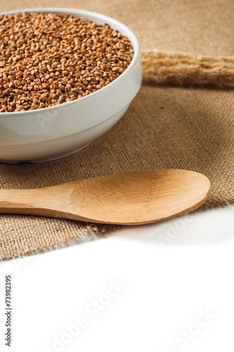 buckwheat and wooden spoon on burlap background. isolate