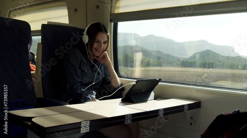 Young woman in headphones watching funny movie on tablet during 