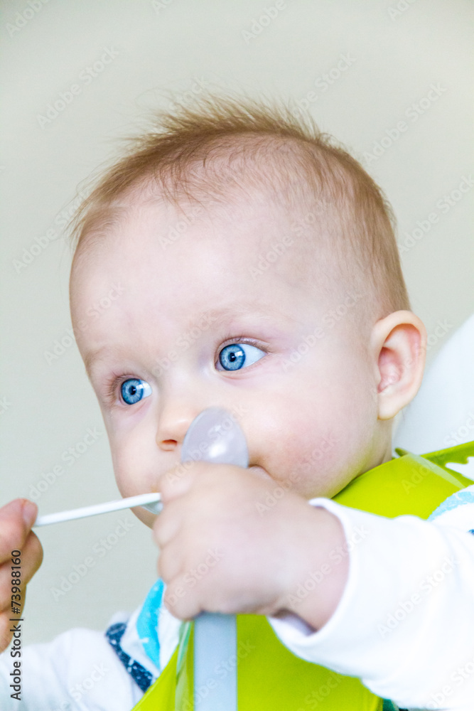 baby boy is eating while sitting on a baby chair baby boy is eating while sitting on a baby chair