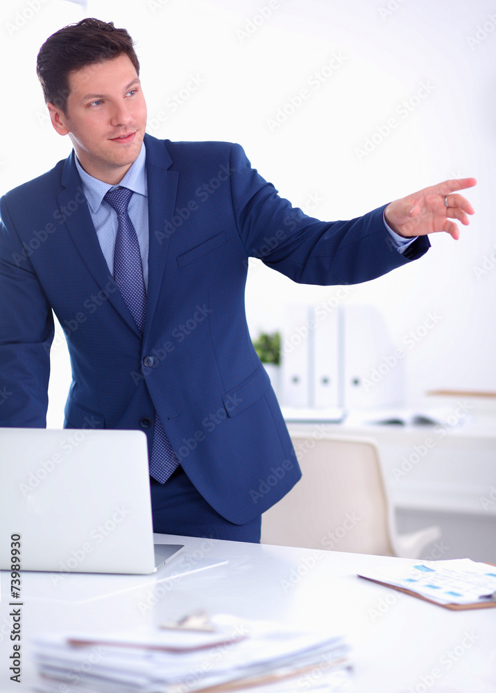 Business man or manager standing against his desk at the office Business man or manager standing against his desk at the office