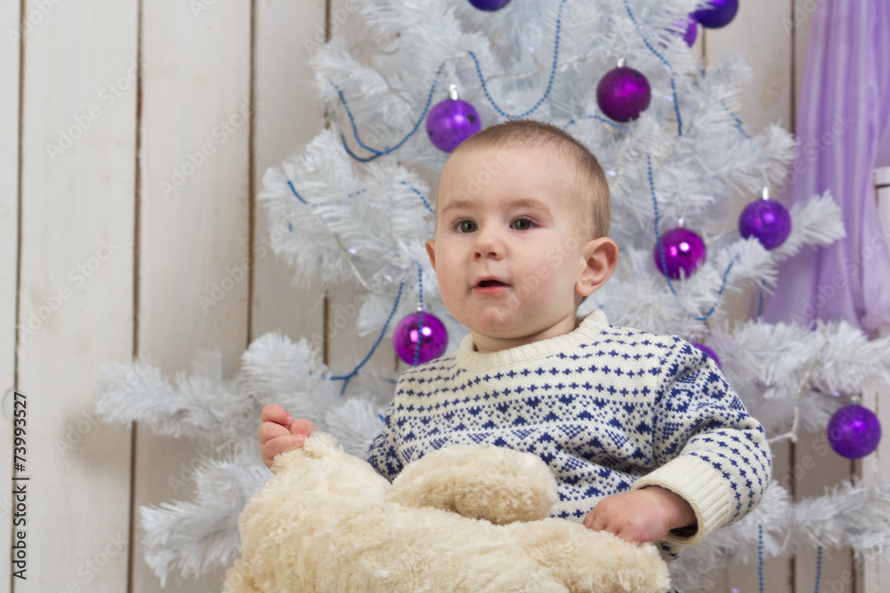 Baby boy under Christmas fir tree