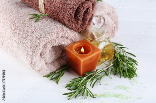 Branches of rosemary and sea salt, towels, candle and bottle