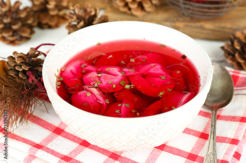 Traditional polish clear red borscht with dumplings in bowl