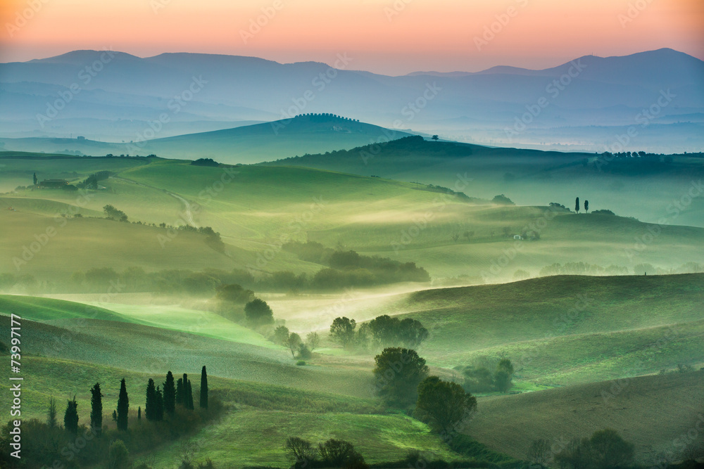 Beautiful view of green fields and meadows at sunset in Tuscany