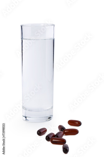 Glass of water and medicine on white background
