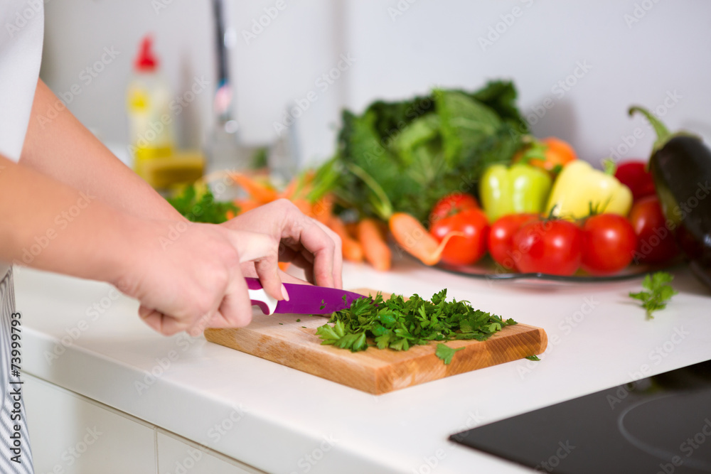 hand with knife cutting food ingredients on wooden board