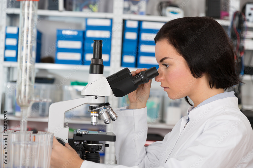 Scientist young woman using a microscope in a science laboratory Scientist young woman using a microscope in a science laboratory