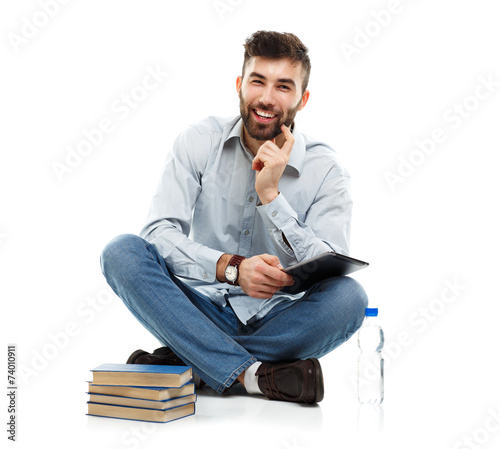 Young bearded smiling man holding a tablet with books and a bott photo