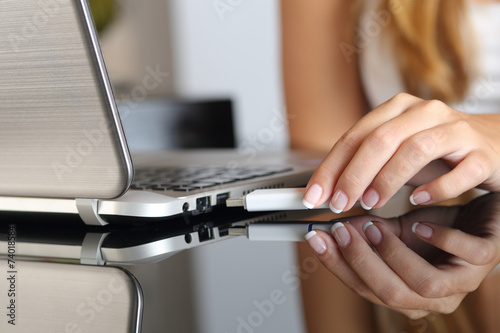 Woman hand plugging an usb  pendrive on a laptop at home