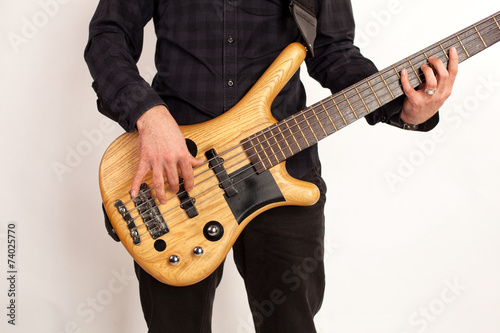 Close up of a brown bass guitar with hands