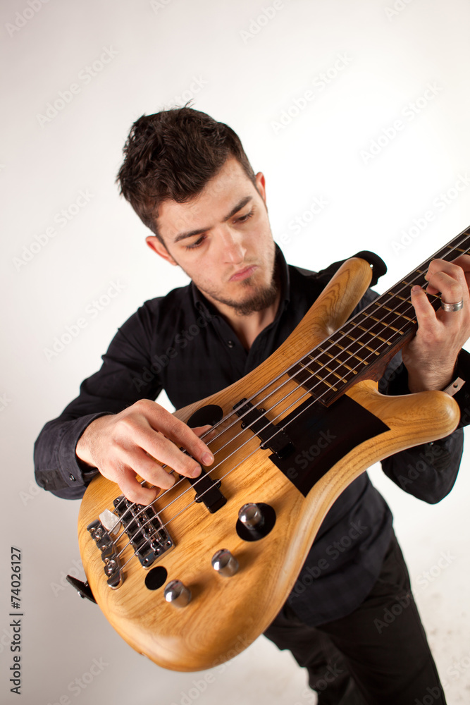 Obraz premium Handsome young bass player holding the bass high