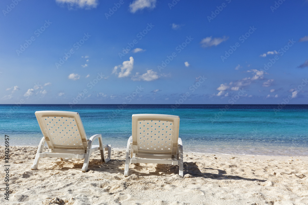 Two white deckchairs at tropical beach