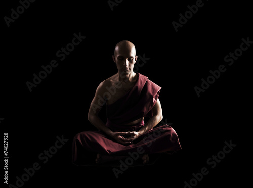 Fotografia buddhist monk in meditation pose over black background