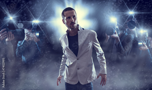 Portrait of attractive male vip celebrity posing in front of pho