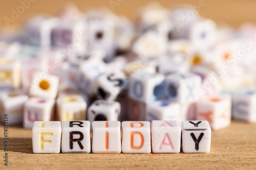 Friday written in letter beads on wood background