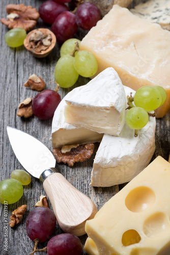assortment of cheeses, grapes and walnuts on a wooden background