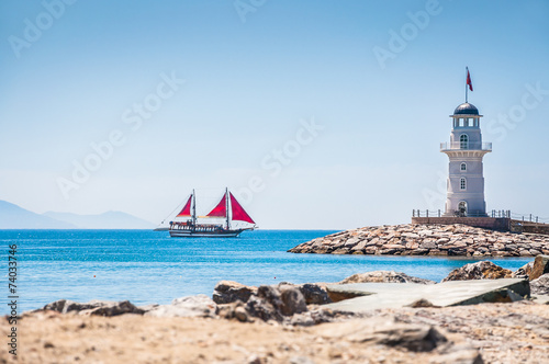 Lighthouse and tourist yacht by the sea