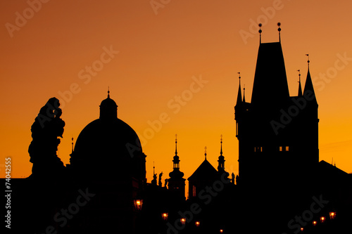 The silhouettes of towers and statues on Charles Bridge in Pragu