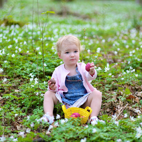 Little girl hunting for chocolate Easter eggs in the forest