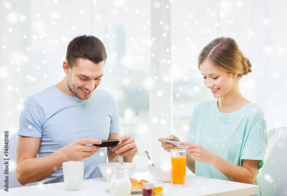 smiling couple with smartphones having breakfast smiling couple with smartphones having breakfast