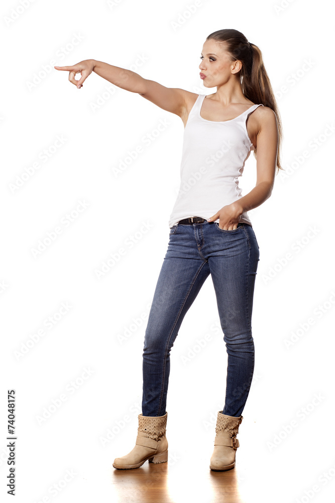 pretty girl in jeans pointing a finger on a white background pretty girl in jeans pointing a finger on a white background
