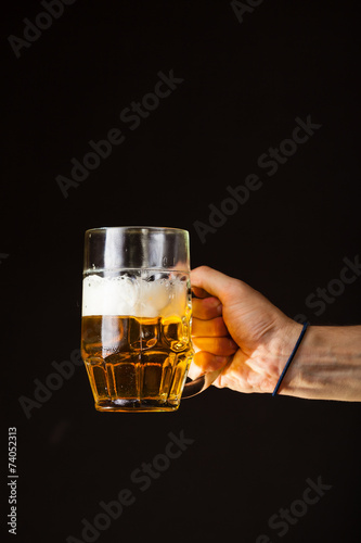 Male hand holding mug of beer