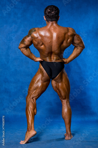 Athletic sports bodybuilder demonstrates posture from the back