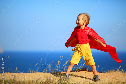 little boy dressed as superhero on the coast