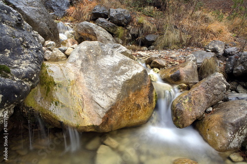 Little waterfall with runnig water in rocks photo