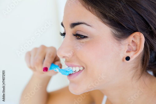 Pretty young woman brushing her teeth. photo