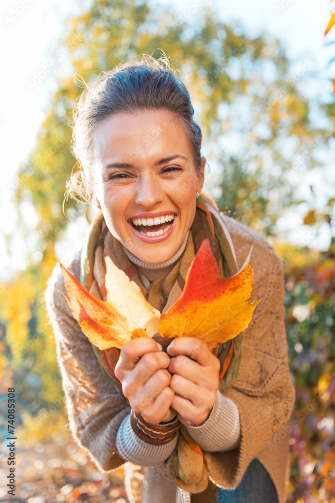 Obraz premium Portrait of happy young woman with autumn leafs outdoors